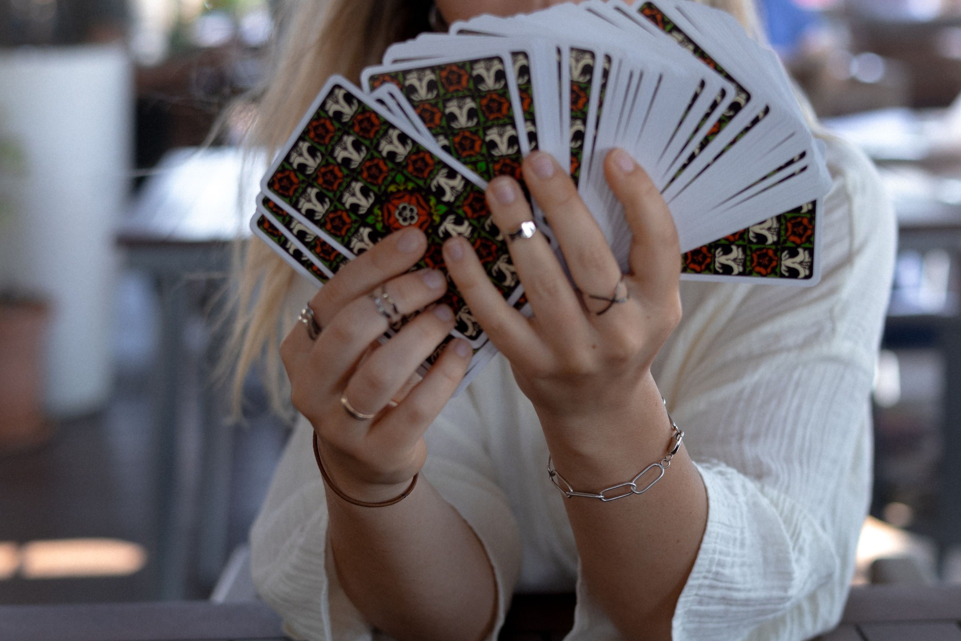 Woman in a light outfit reads Tarot cards on a table in a cafe
